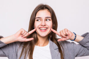 Virtual dental consultation - young woman pointing at her smile